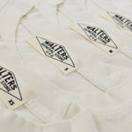 Three folded off-white cotton t-shirts stacked diagonally, showing the collar and printed 'Walters' brand labels.