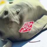 An olive green baseball cap with a red embroidered patch reading 'WALTERS GENERAL STORE U.S.A