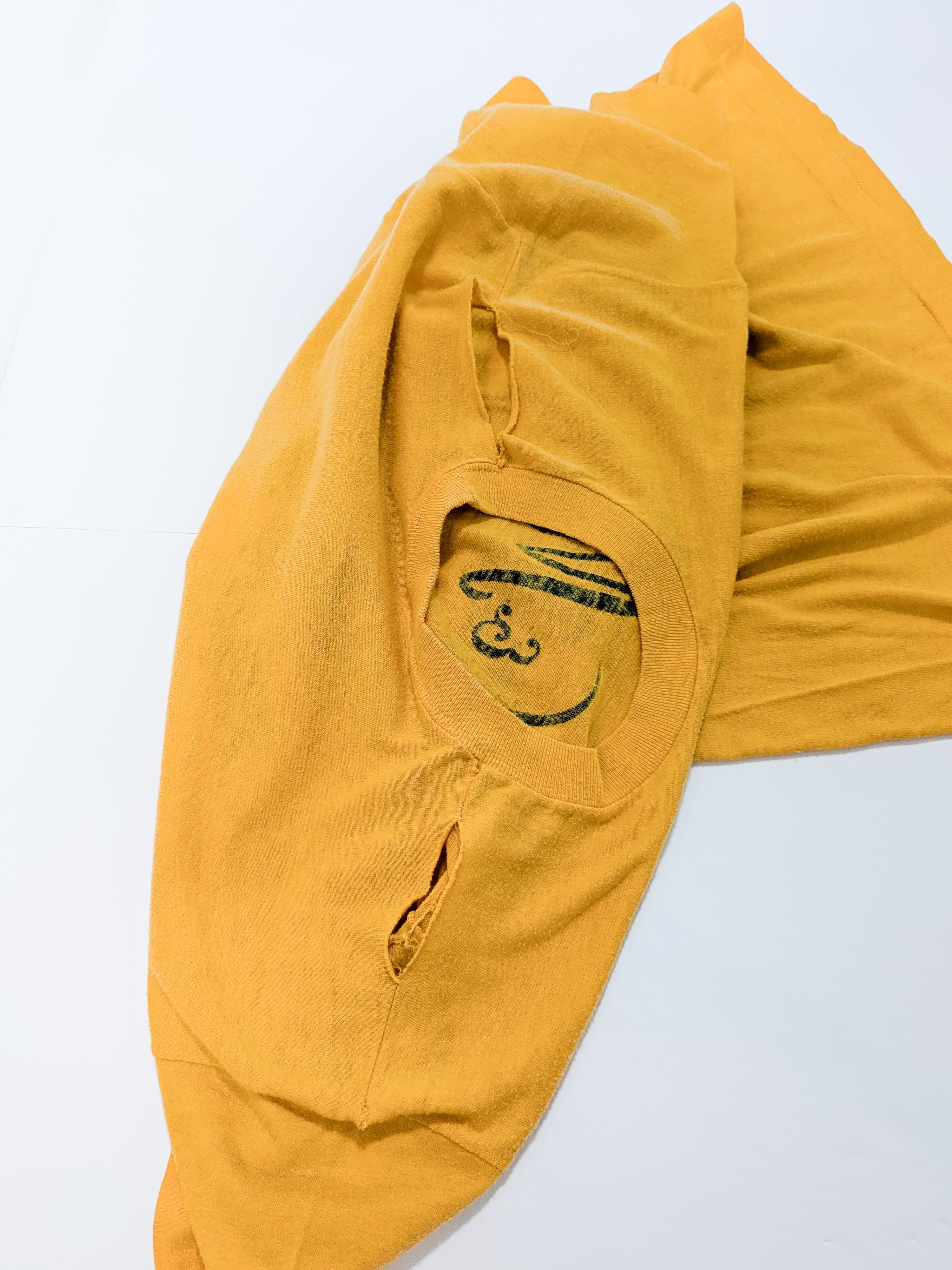 A folded mustard yellow t-shirt with a black printed graphic on the chest, displayed on a clean white background.